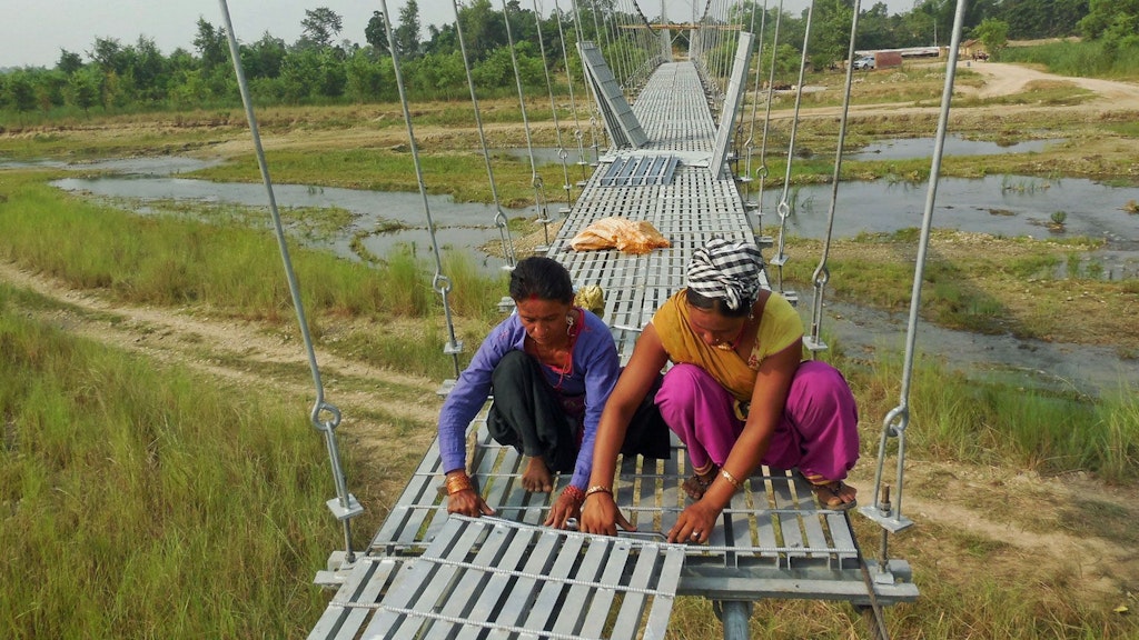 Des femmes installent des éléments de plancher du pont Ghurswaghat à Kanchanpur.