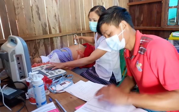  A man and a woman visit a patient and perform an ultrasound examination.