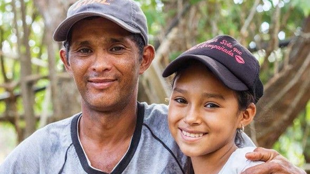 Un père et sa fille rient face à la caméra.