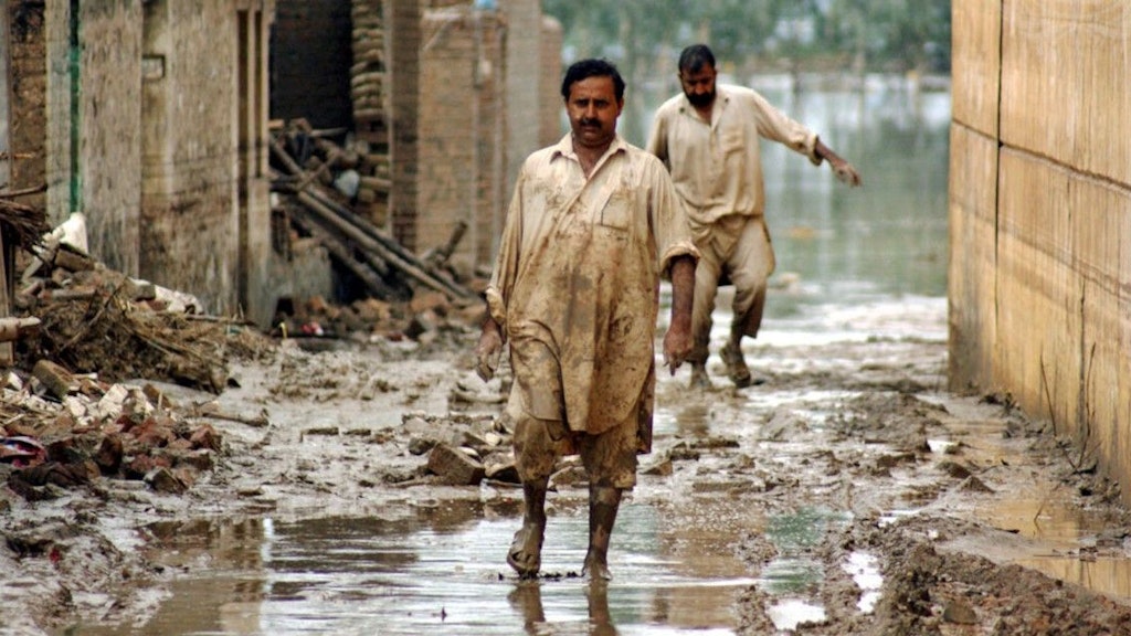 Des victimes des inondations de 2010 au Pakistan marchent dans les rues inondées de la ville de Nowshera, dans le nord-ouest du pays.