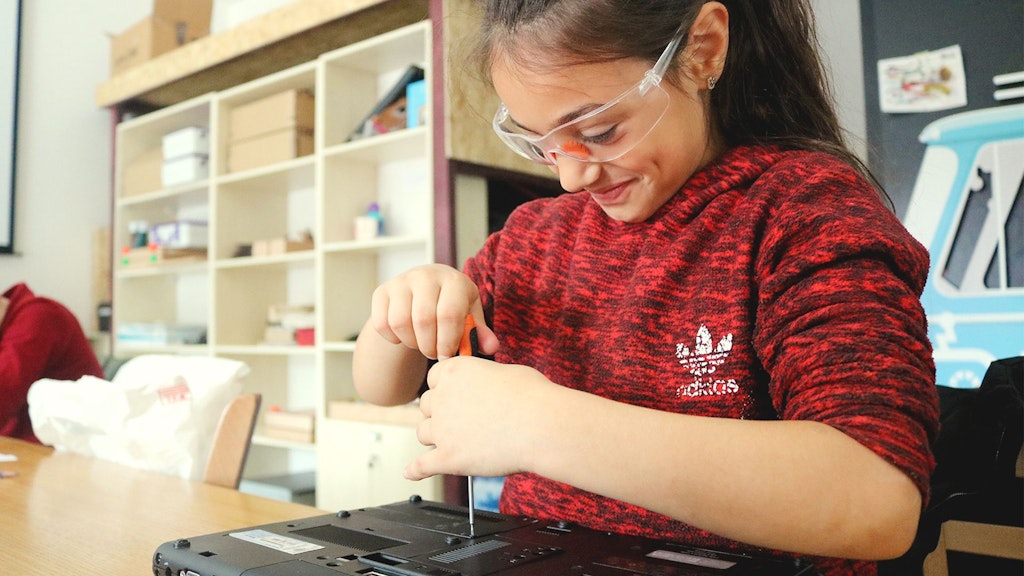 Une jeune participante à un projet de la DDC répare un ordinateur.