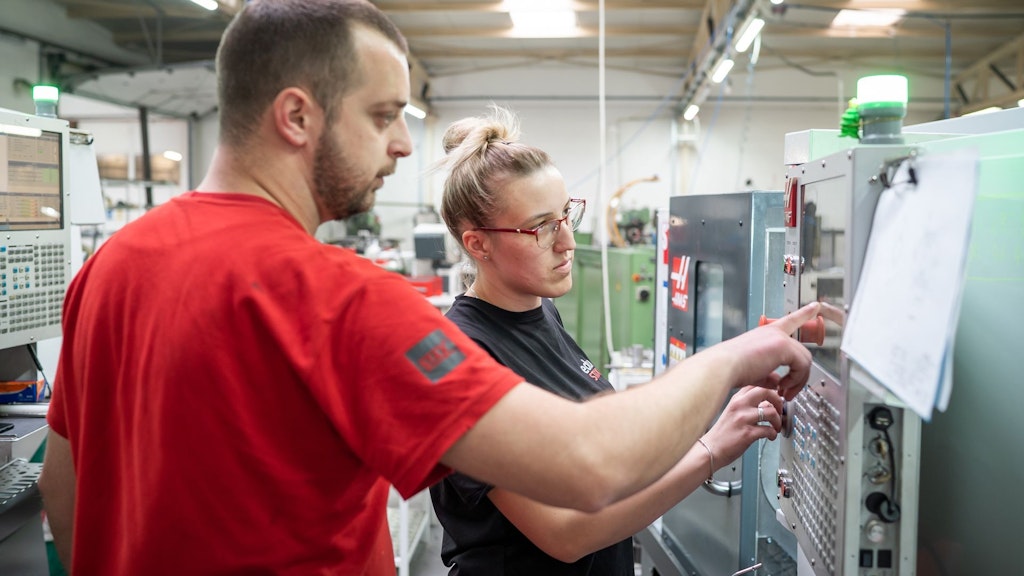 Un formateur explique à une élève comment utiliser une machine.
