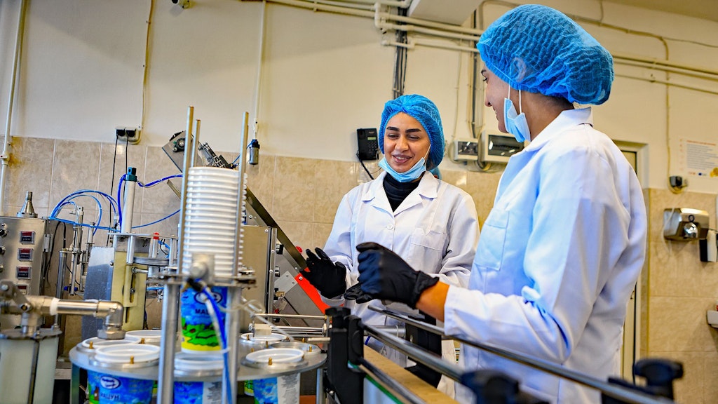 En Arménie, deux jeunes femmes se tiennent devant une remplisseuse de produits laitiers. Elles acquièrent des connaissances pratiques en matière de sécurité alimentaire et de contrôle qualité.