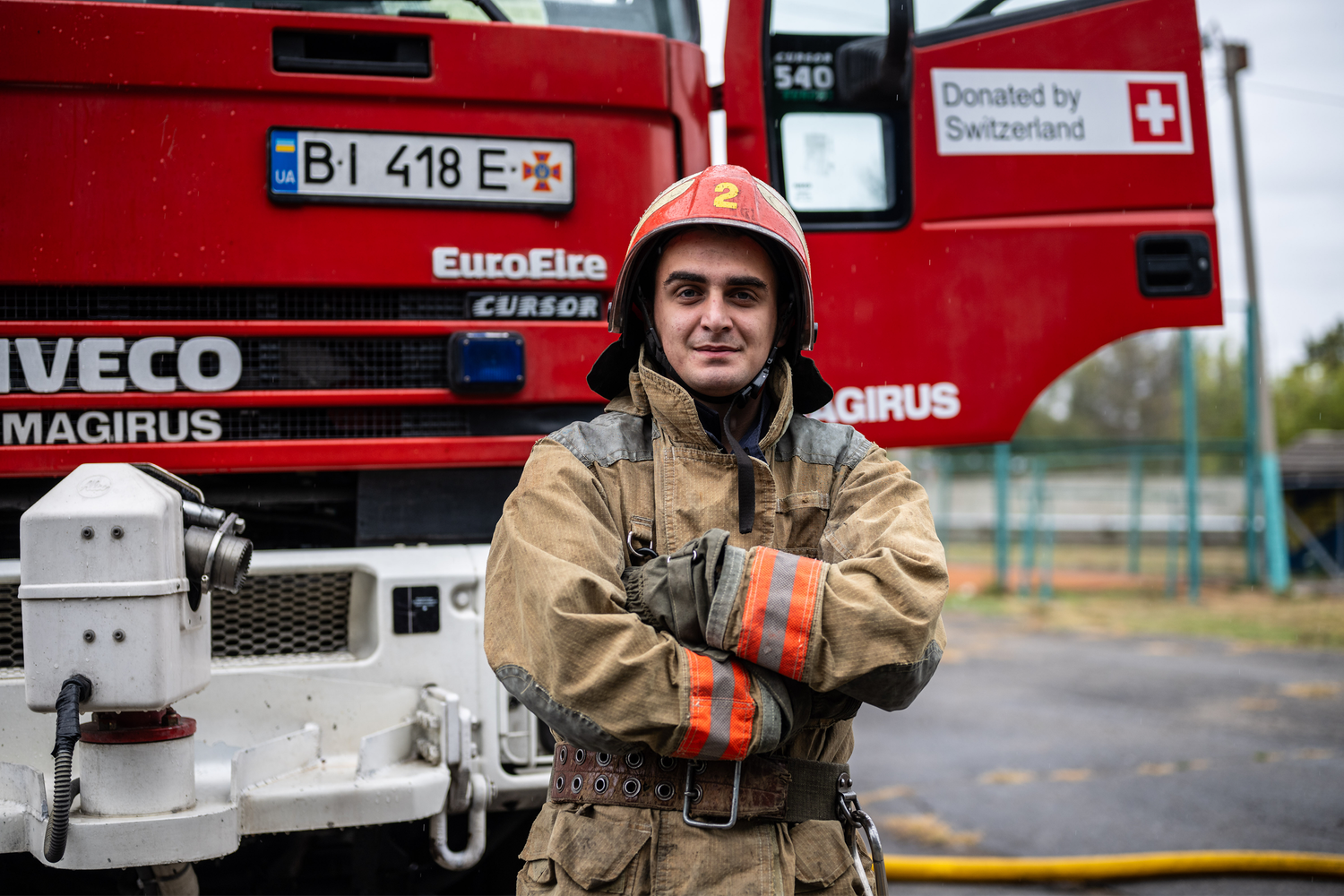 Ein ukrainischer Feuerwehrmann vor einem von der Schweiz gespendeten Löschfahrzeug – Sinnbild der Schweizer Unterstützung für die Rettungsdienste in der Ukraine.