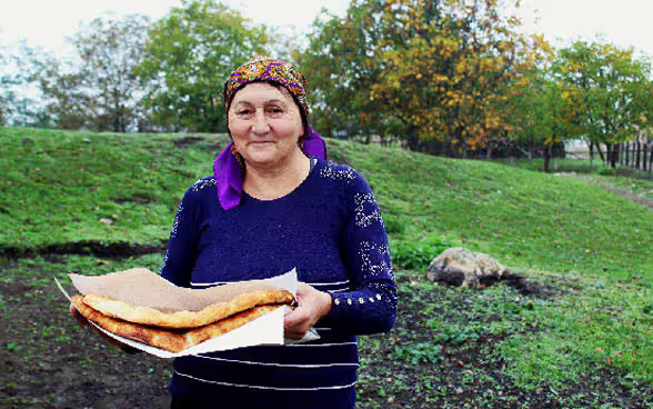 Eine Frau trägt frisches Fladenbrot.