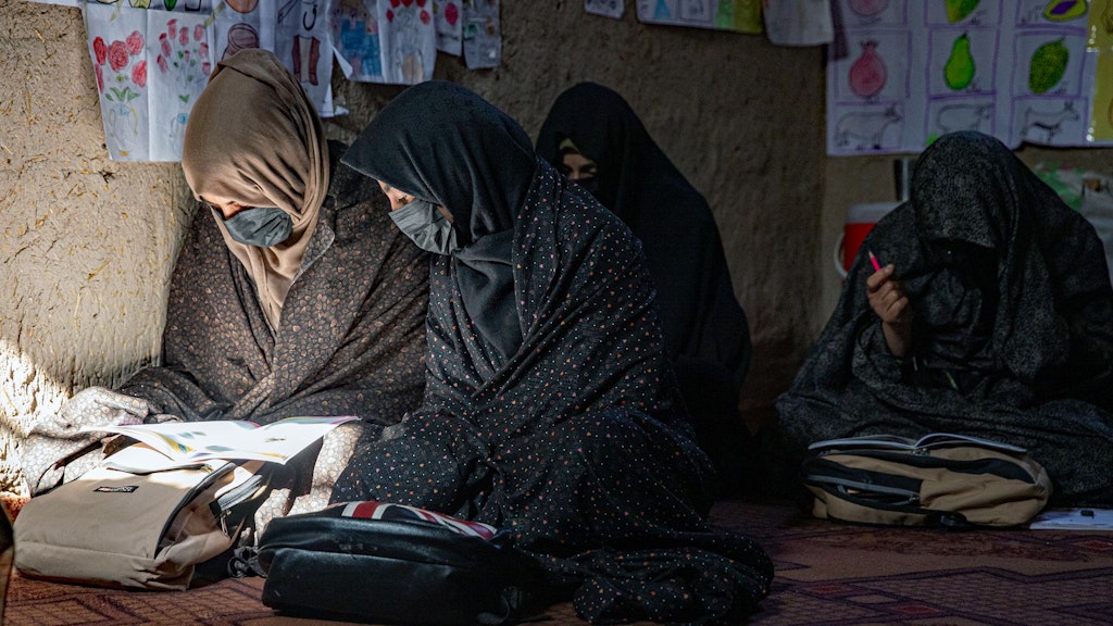 Mädchen in Afghanistan lesen in einem dunklen Raum in ihren Büchern.  