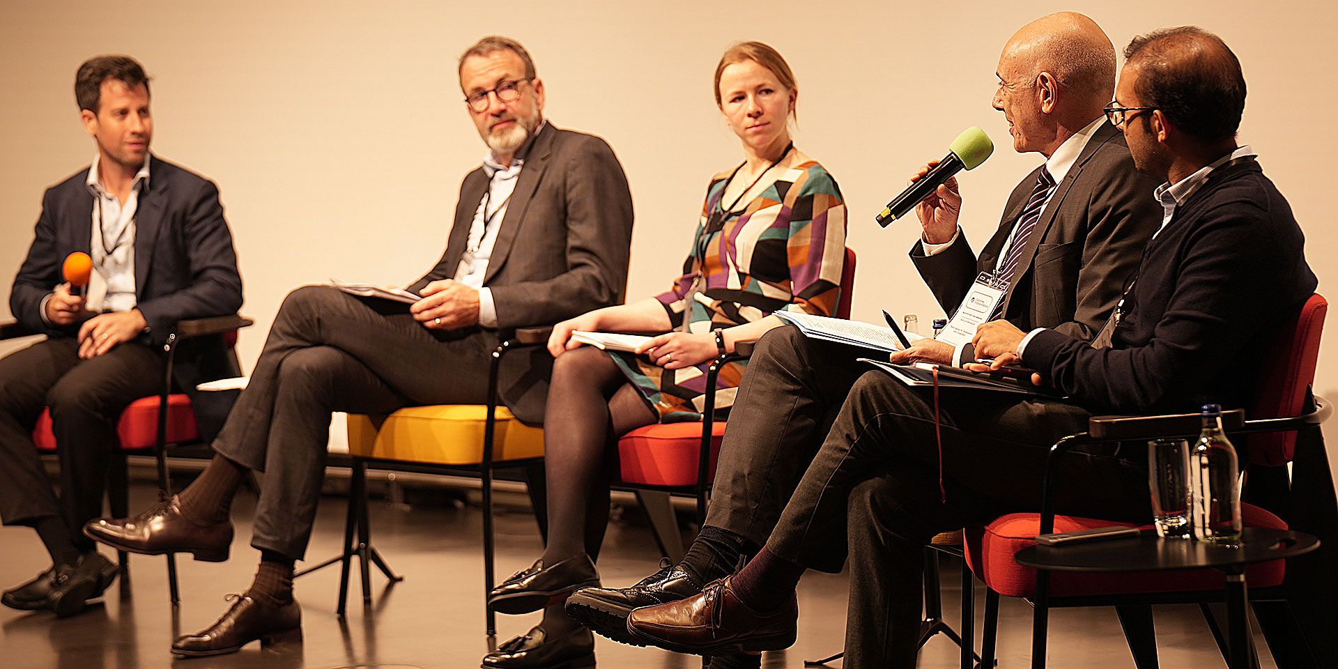  Vier Männer und eine Frau nehmen an einer Podiumsdiskussion teil.