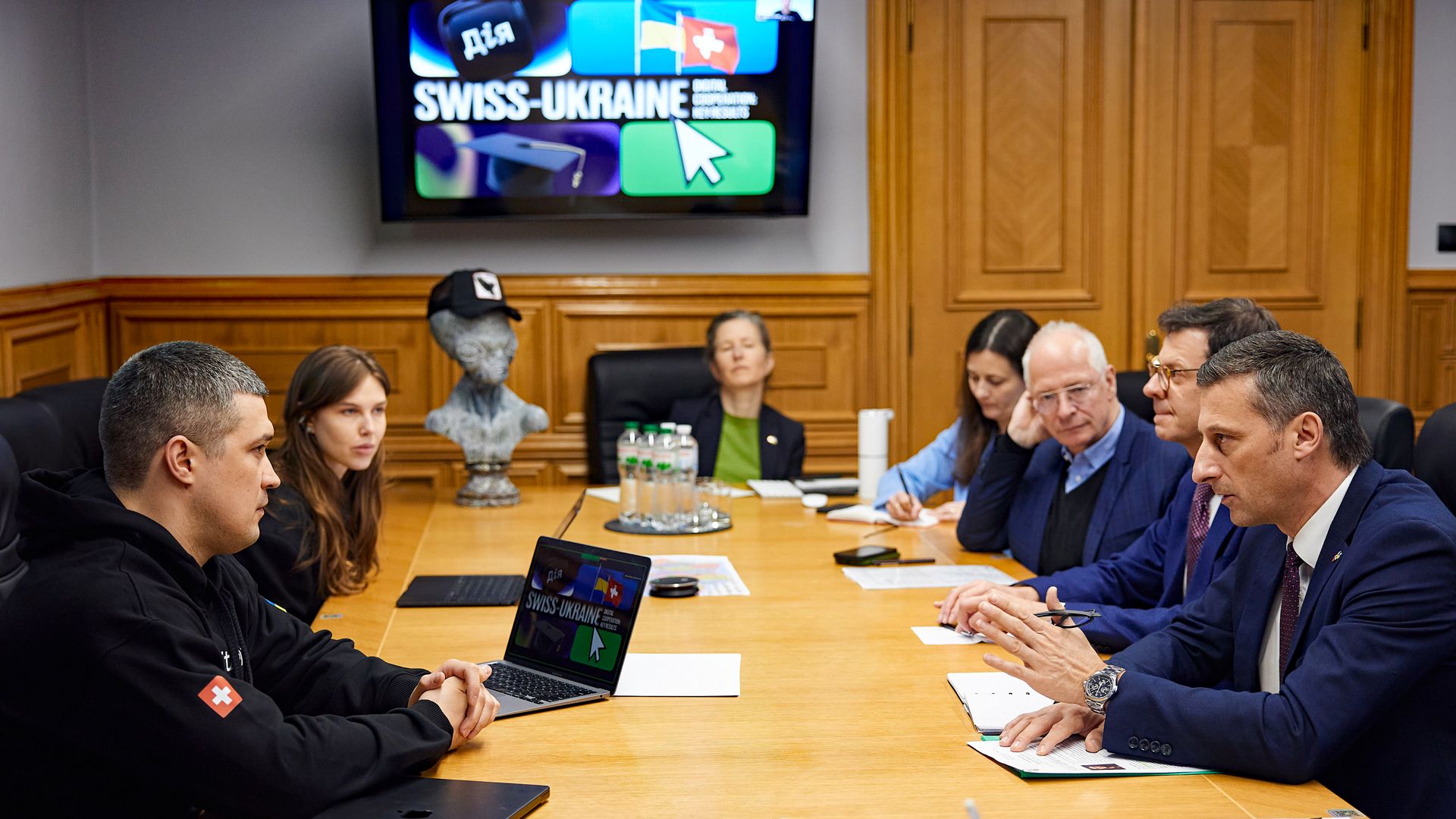 Die ukrainische und die Schweizer Delegation sitzen gemeinsam an einem Tisch und diskutieren.