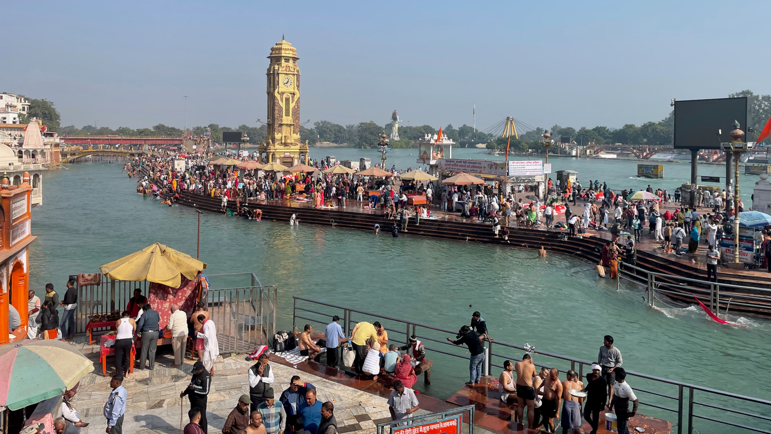 Der Fluss Ganges zu beiden Seiten von Badeufern eingerahmt mit zahlreichen Hindus am Baden. 