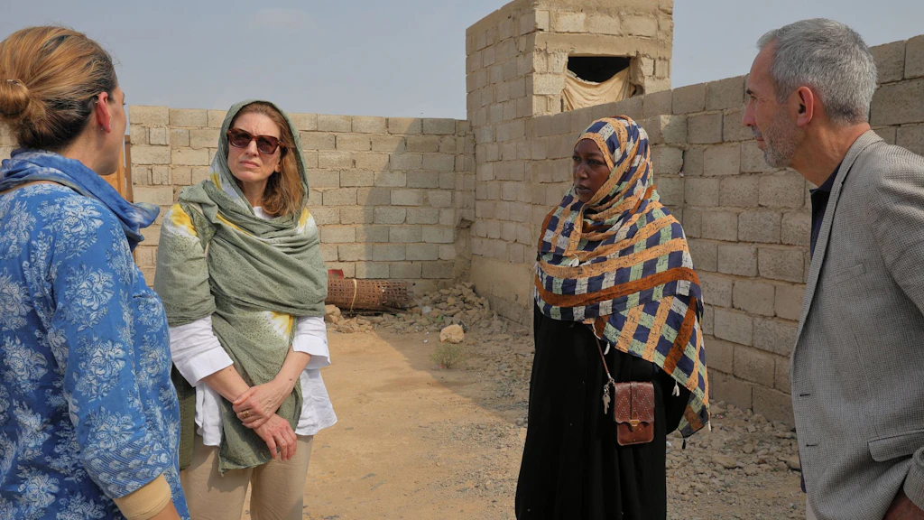 Four people are standing in a courtyard surrounded by a wall, talking to each other. Valérie Liechti is second from the left.  