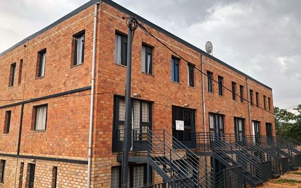 Several black stairways leading up to the front doors of a multi-storey building made of bricks.