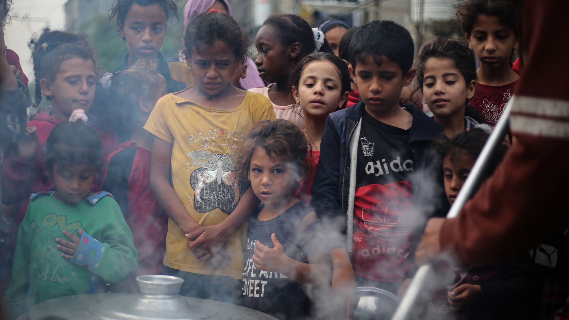 A group of children waiting for a food distribution.