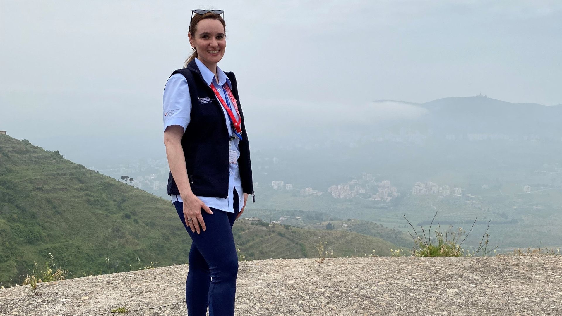 Dana Aljarah poses in front of a mountainous landscape.