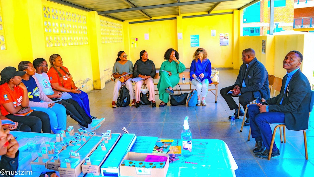 People sitting in a circle, in front of them a table with medical supplies