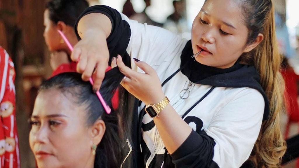 Phally smooths a bride's hair, holding two hair clips in her mouth.