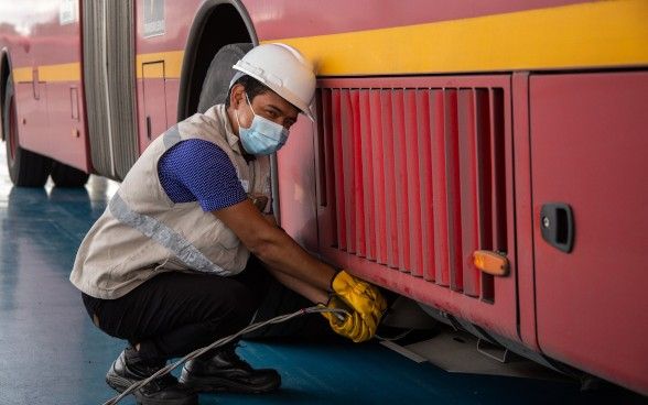 Worker kneeling next to electric bus.