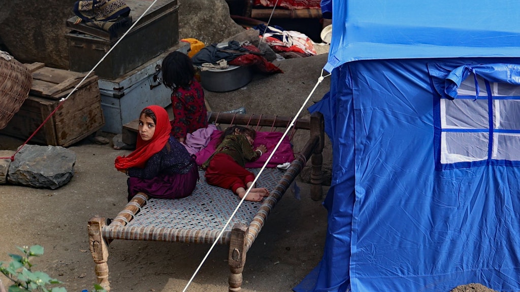 Children sitting in front of an refugee shelter. 