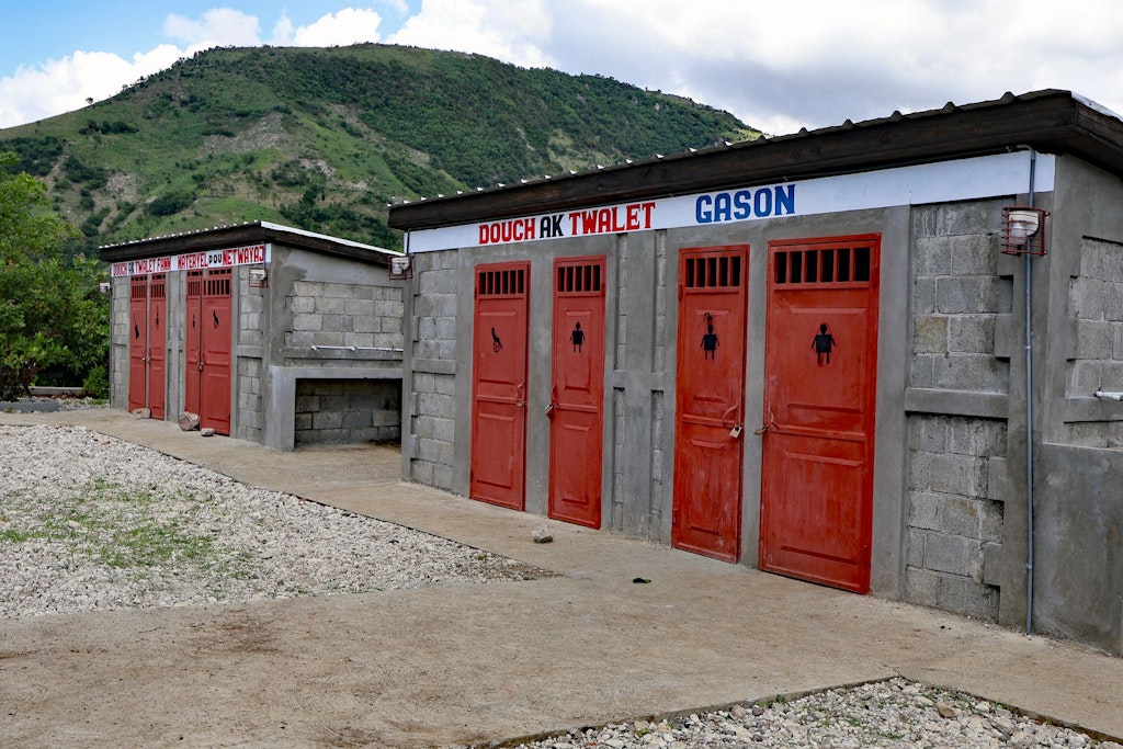 Two stone huts, each with four doors marked for toilets, showers and cleaning equipment.