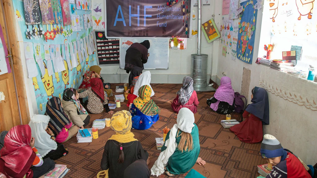 A classroom with girls sitting on the floor.
