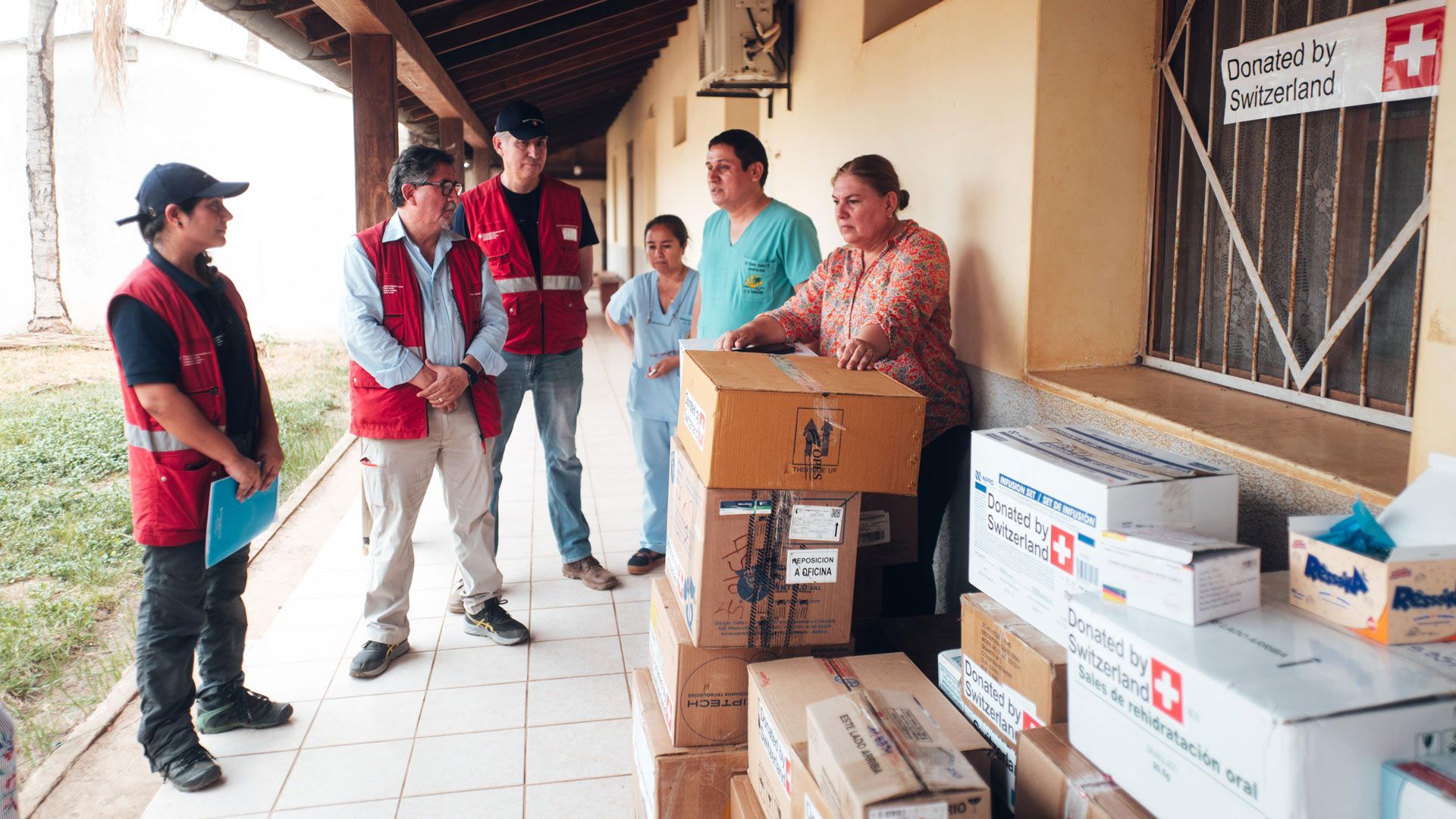 Three members of the team hand over boxes of medicines to local health workers.
