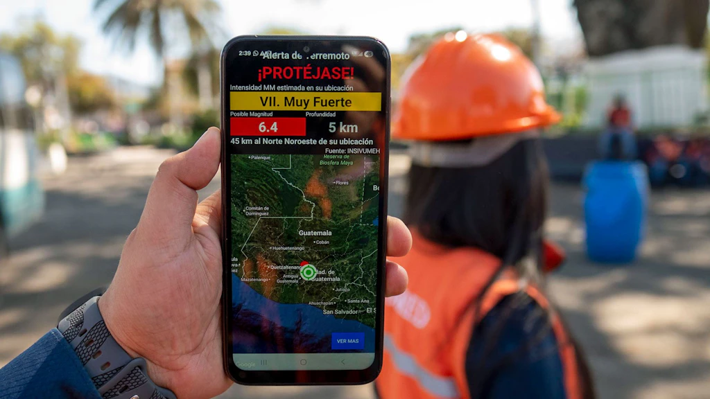 A person holding a smartphone on which the app can be seen.