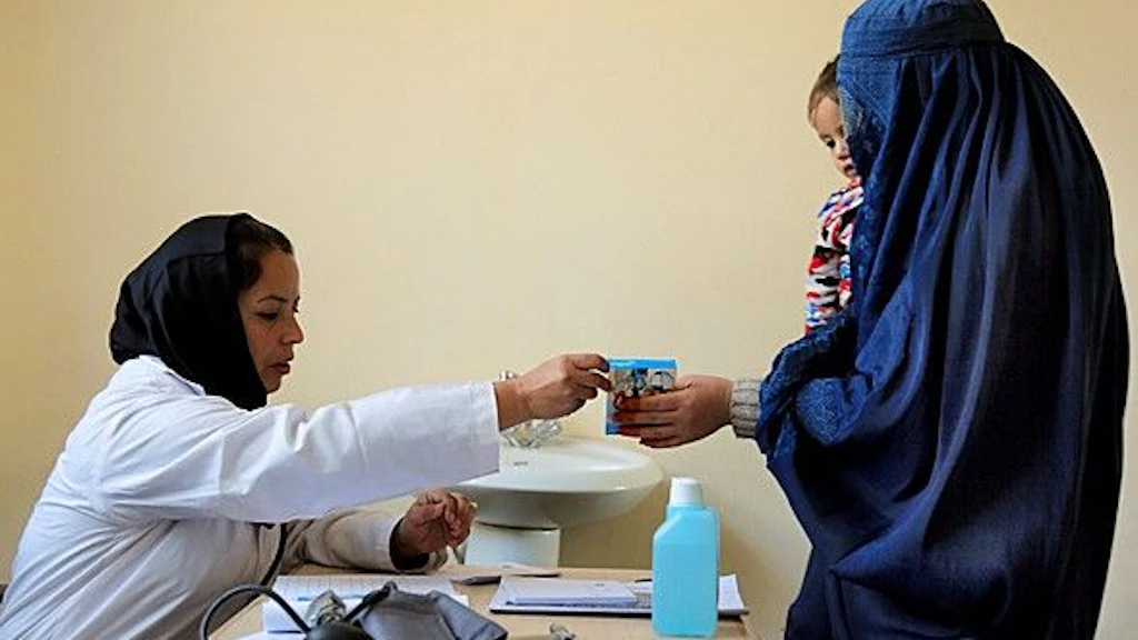 A mother with her child in her arms receives medication from a hospital employee in Kabul, Afghanistan. 