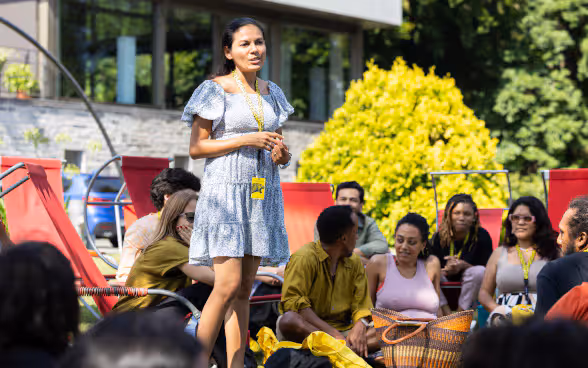 A woman stands in a group of people and talks.