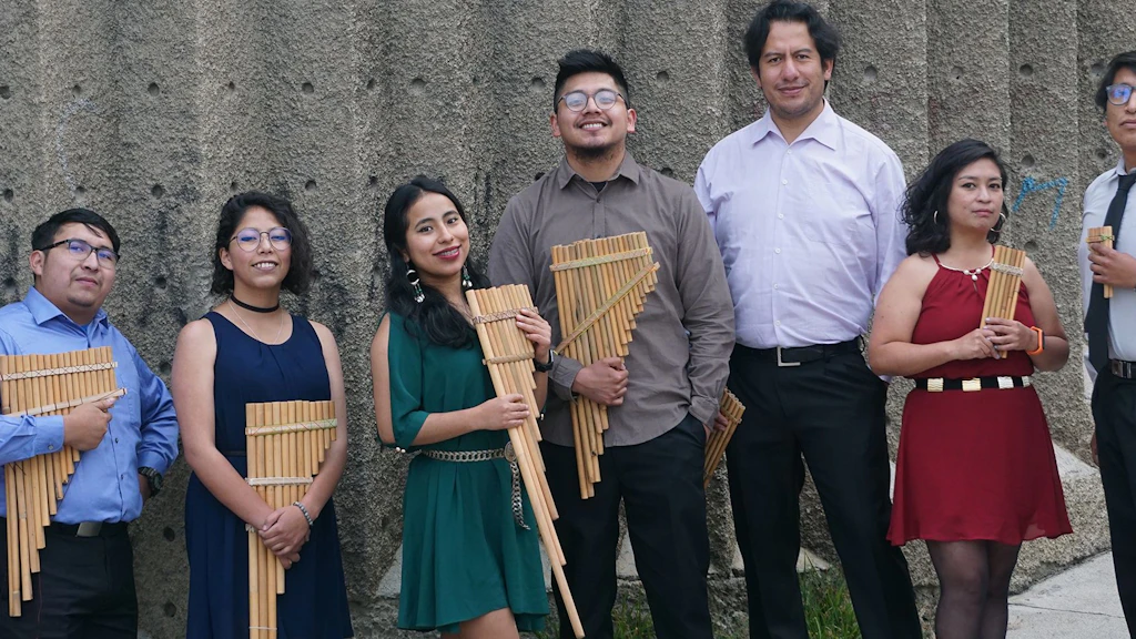 Les sept musiciens de l'Ensemble OEIN sont debout et tiennent dans leurs mains des flûtes de pan. 
