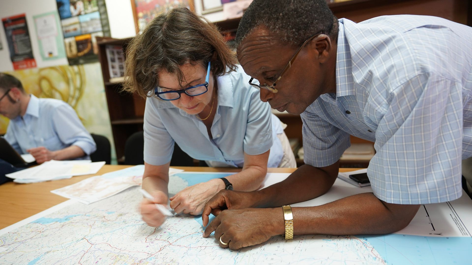 Une spécialiste du Corps suisse d’aide humanitaire étudie une carte avec un expert du Mozambique.