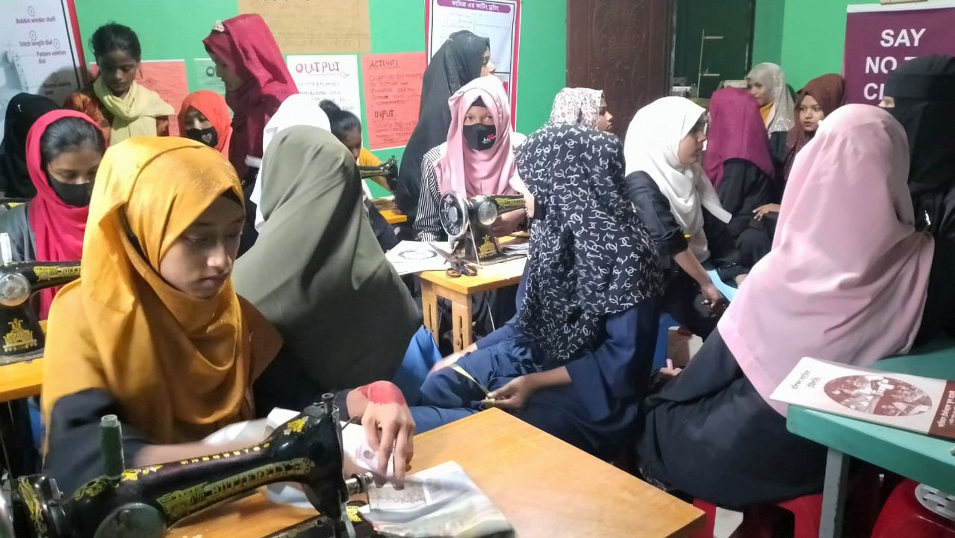 Assises devant des machines à coudre, des jeunes filles participent à un atelier de couture dans le cadre d’un programme de formation professionnelle.