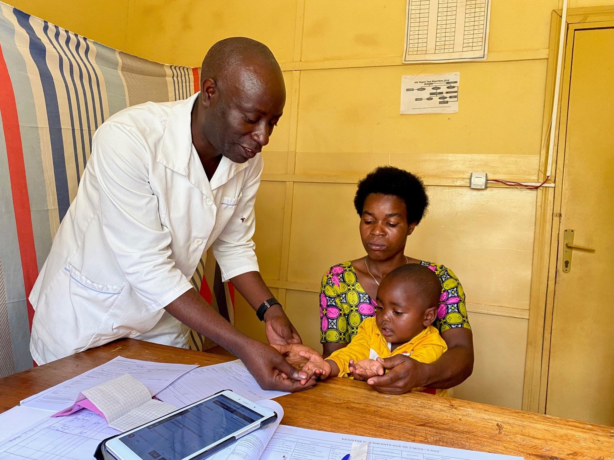 Un médecin examine un enfant dans les bras de sa mère.