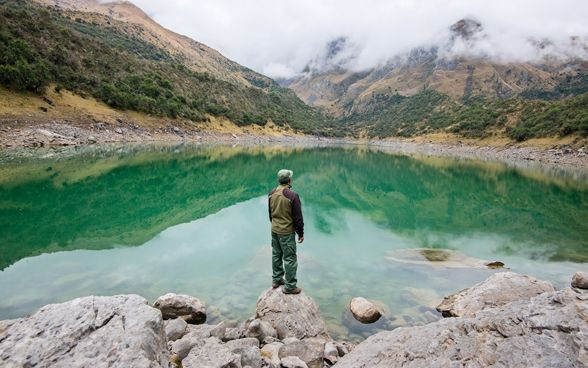  Un homme se tient au bord d’un lac de montagne.