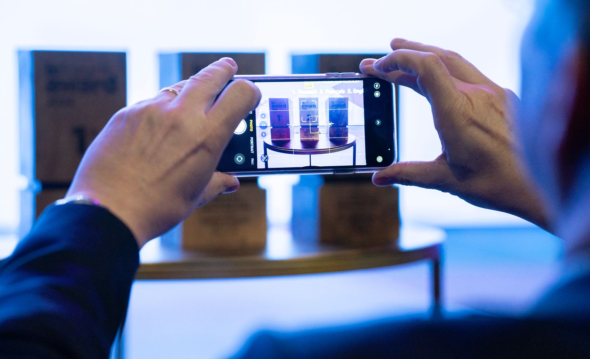 Gros plan sur les mains d’une personne qui tient un téléphone portage et prend une photo. 