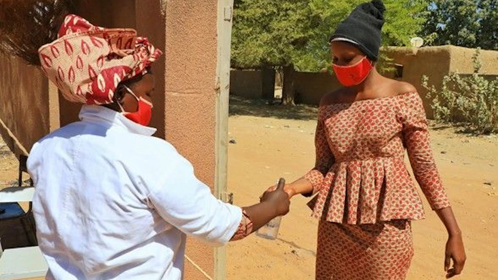 Deux femmes africaines portent des masques et se désinfectent les mains à cause du Covid-19.
