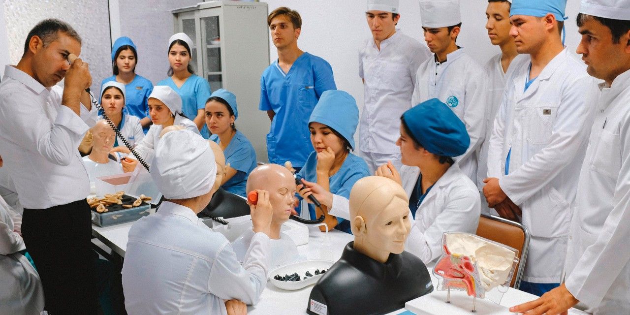Du personnel médical tadjik effectue une formation. Sur la table se trouvent des mannequins et instruments médicaux.