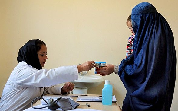 Une mère avec son enfant dans les bras reçoit un médicament d'un employé de l'hôpital à Kaboul/Afghanistan. 