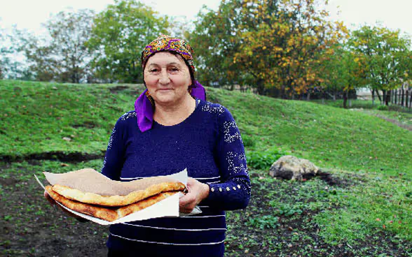 Una donna che tiene tra le mani del pane fresco.
