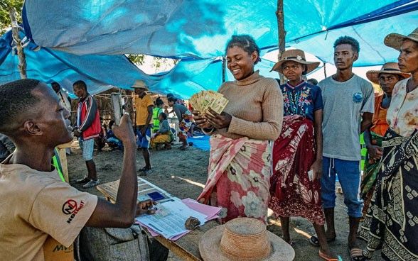 Una donna in Madagascar riceve denaro contante per acquistare generi alimentari e articoli per la casa per la sua famiglia a seguito di una prolungata siccità.