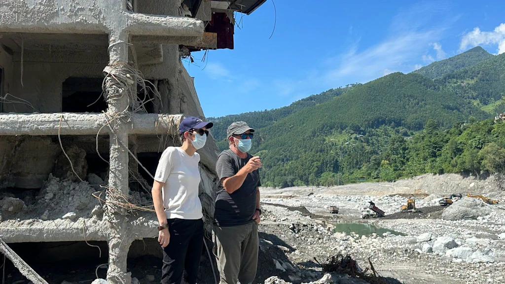 Una donna e un uomo in piedi davanti a un edificio in rovina.