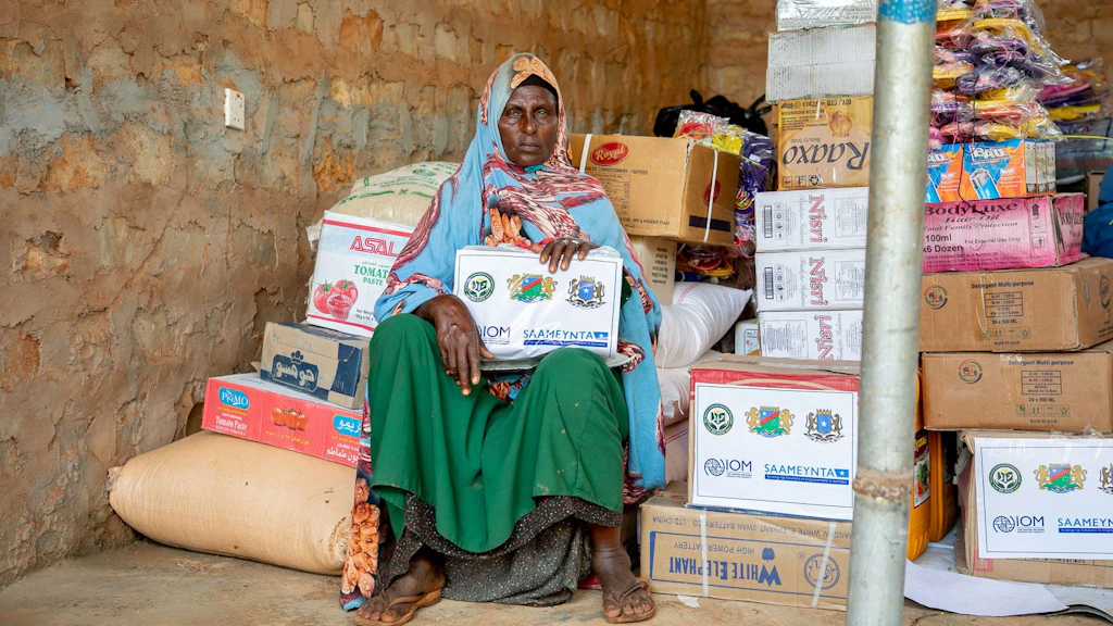 Una beneficiaria del progetto «Saameynta» seduta davanti al suo negozio nel campo di reinsediamento di Barwaaqo, in Somalia.