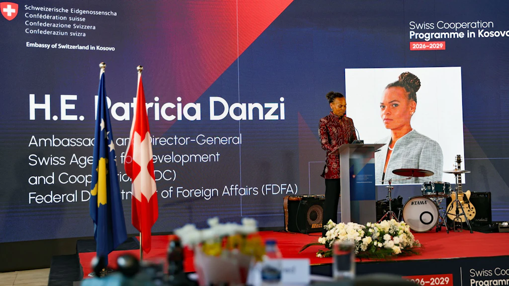 Una donna parla a un leggio davanti a un pannello con la scritta Swiss Cooperation Programme in Kosovo 2026-2029.