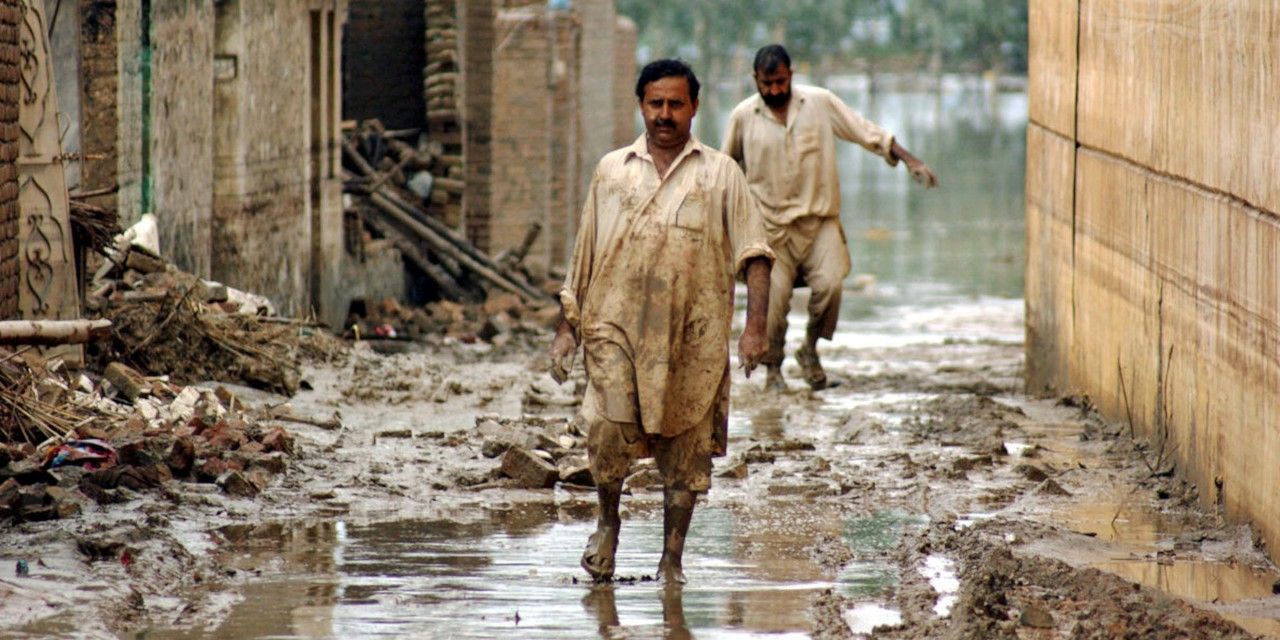 Vittime delle alluvioni del 2010 in Pakistan camminano per le strade allagate della città nord-occidentale di Nowshera.