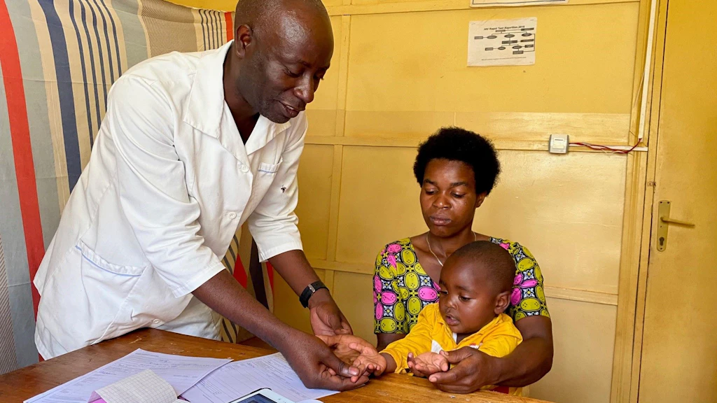 Un medico visita un bambino tra le braccia di sua madre.