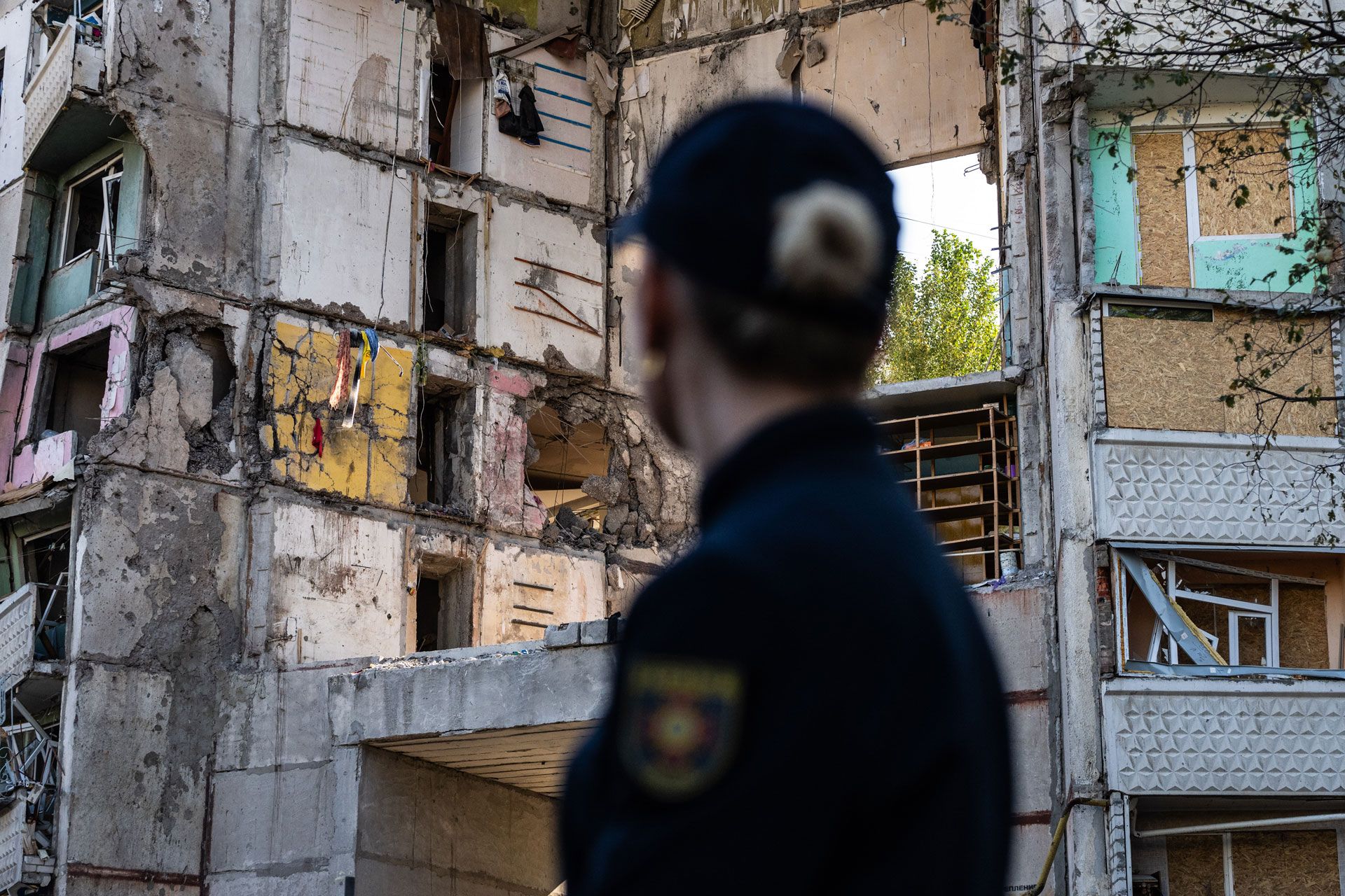 Un membro della squadra di protezione civile ucraina davanti a una casa danneggiata.