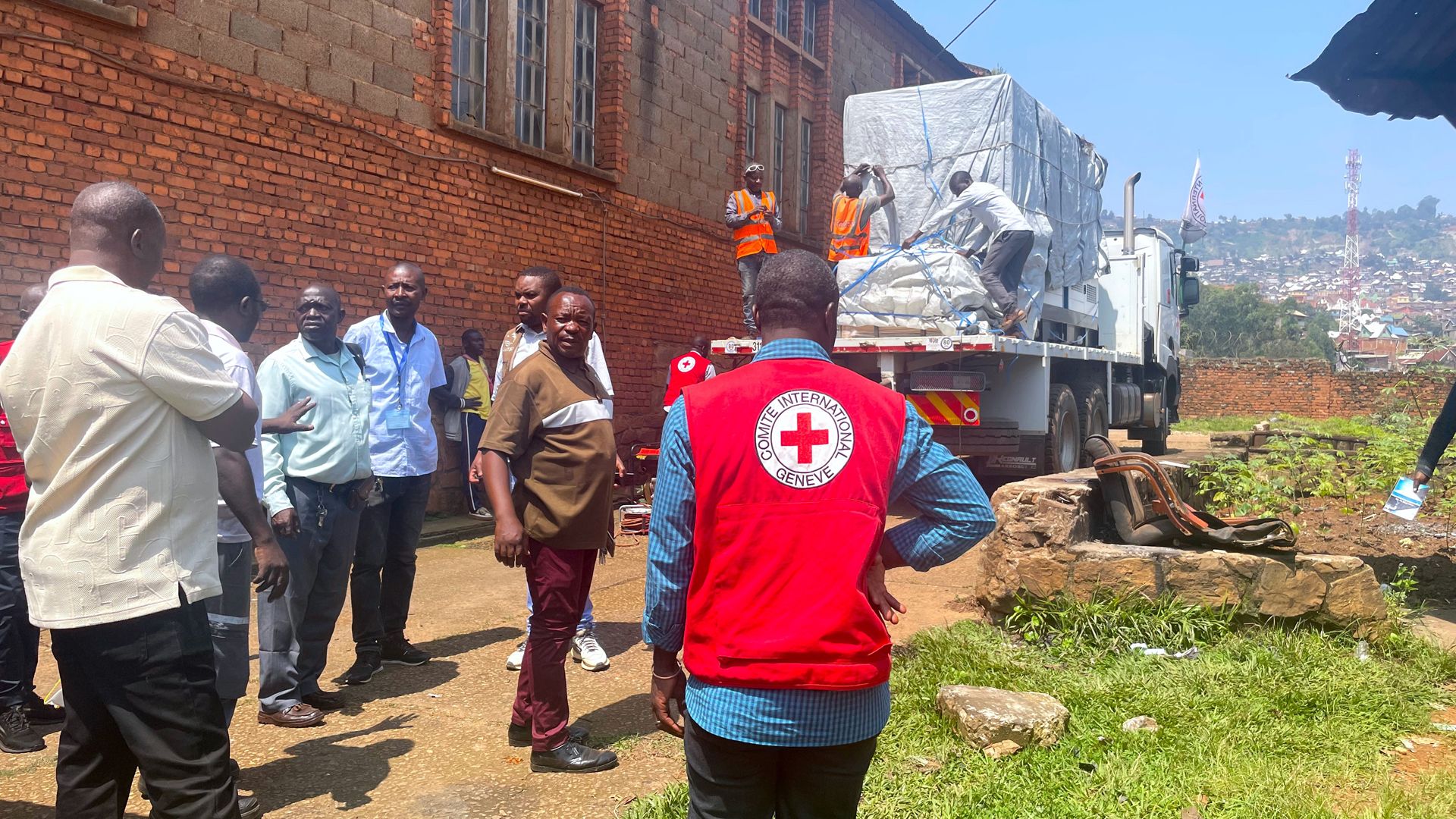 Un generatore imballato è visibile su un camion del CICR, mentre i dipendenti del CICR e REGIDESCO osservano.
